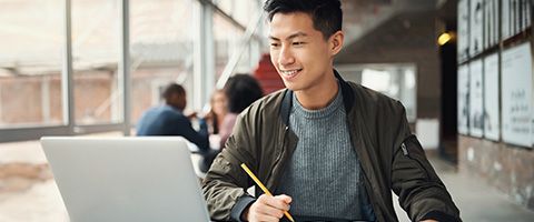 Man looking at a laptop with a pencil 