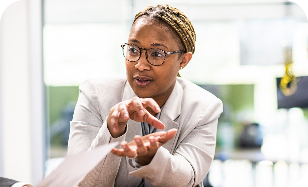  A woman engaged in a conversation making expressive hand gestures with an office environment in the background