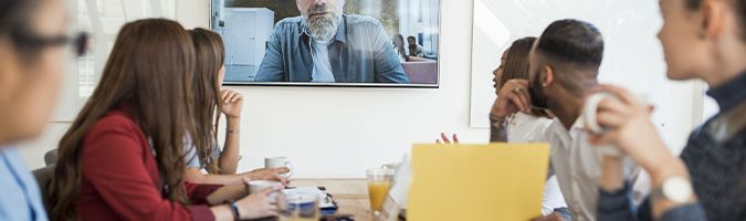 Group of business people sitting  in a conference room listening to a gentlemen on a video call