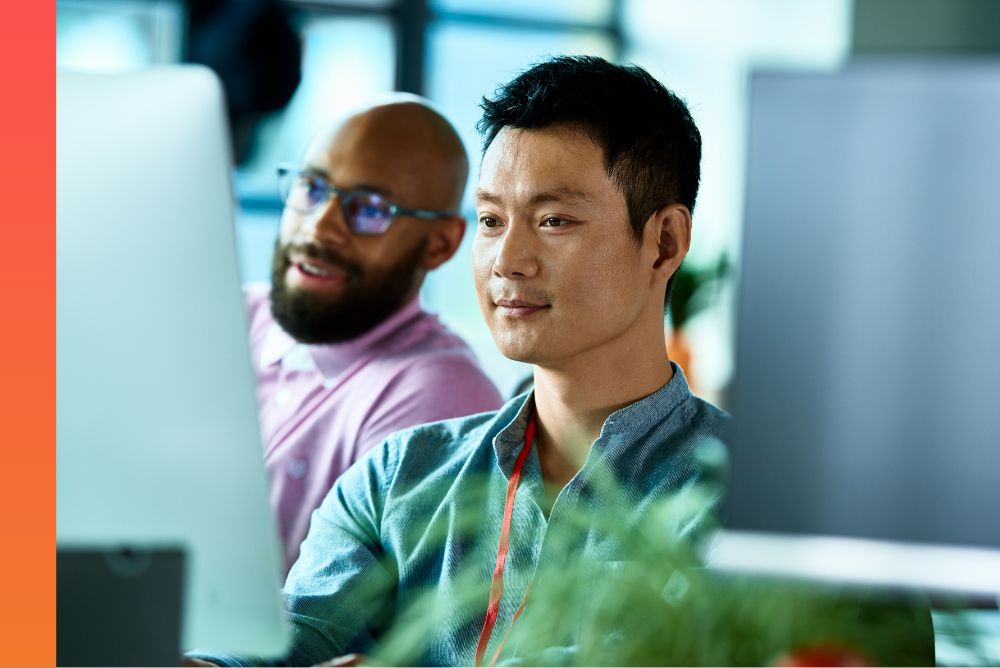 Two people viewing a computer monitor. 