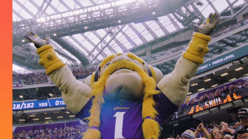 Minnesota Vikings mascot Victor the Viking raises his hands to signal a touchdown inside a crowded U.S. Bank stadium.