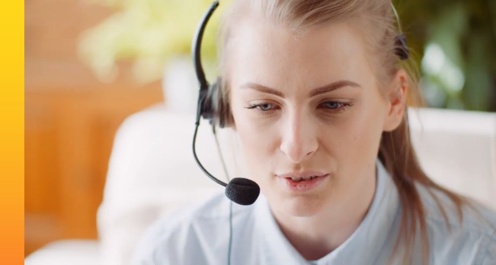 Woman in a white shirt sitting down while talking on her headset