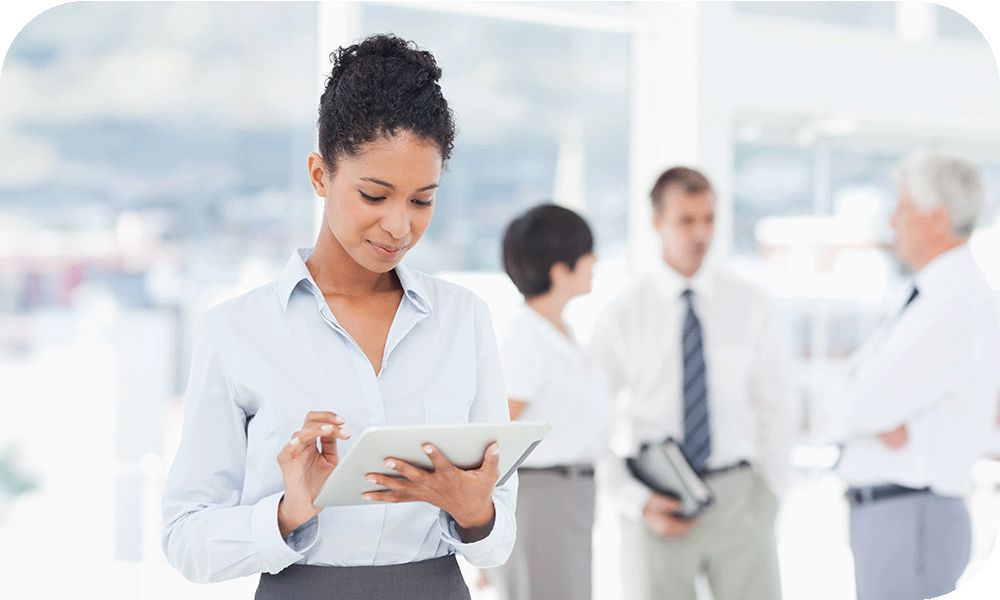 Businessperson looking at a smart tablet standing in front of three people talking.