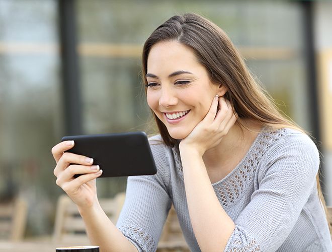 Woman sitting outside while watching something on her phone