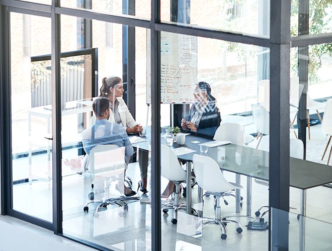 Draufsicht auf einen hell erleuchteten Konferenzraum mit drei Geschäftsleuten, die an einem Tisch sitzen