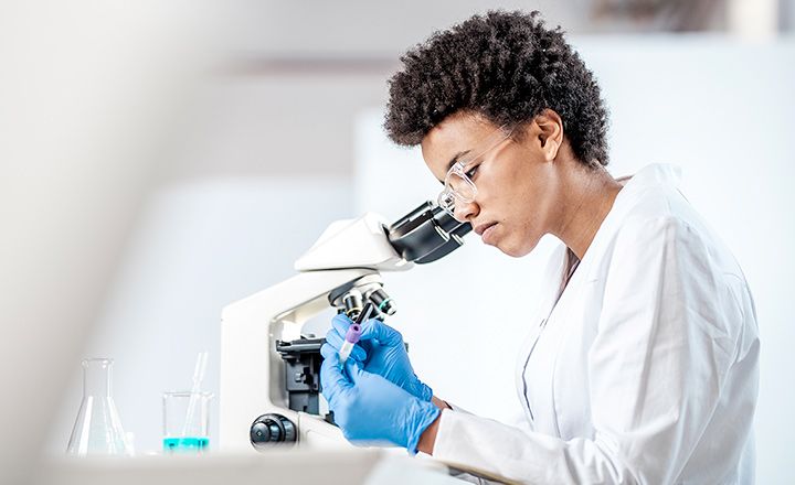 Cientista trabalhando em um laboratório ao lado de um microscópio 